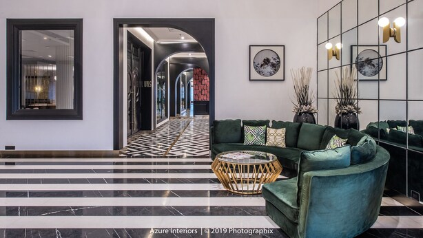 Eine moderne Lobby mit einem geometrisch gemusterten Boden, einem grünen Sofa und einem dekorativen Couchtisch.