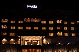 Un hotel con un letrero destacado que dice "Clarke Hotel". Tiene varios balcones con barandillas y ventanas, además de un área de entrada bien iluminada.