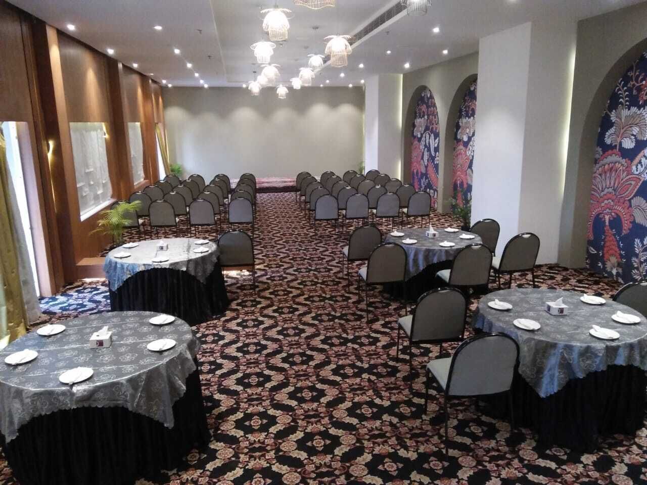 Un salón de conferencias con mesas redondas, sillas y piso alfombrado.