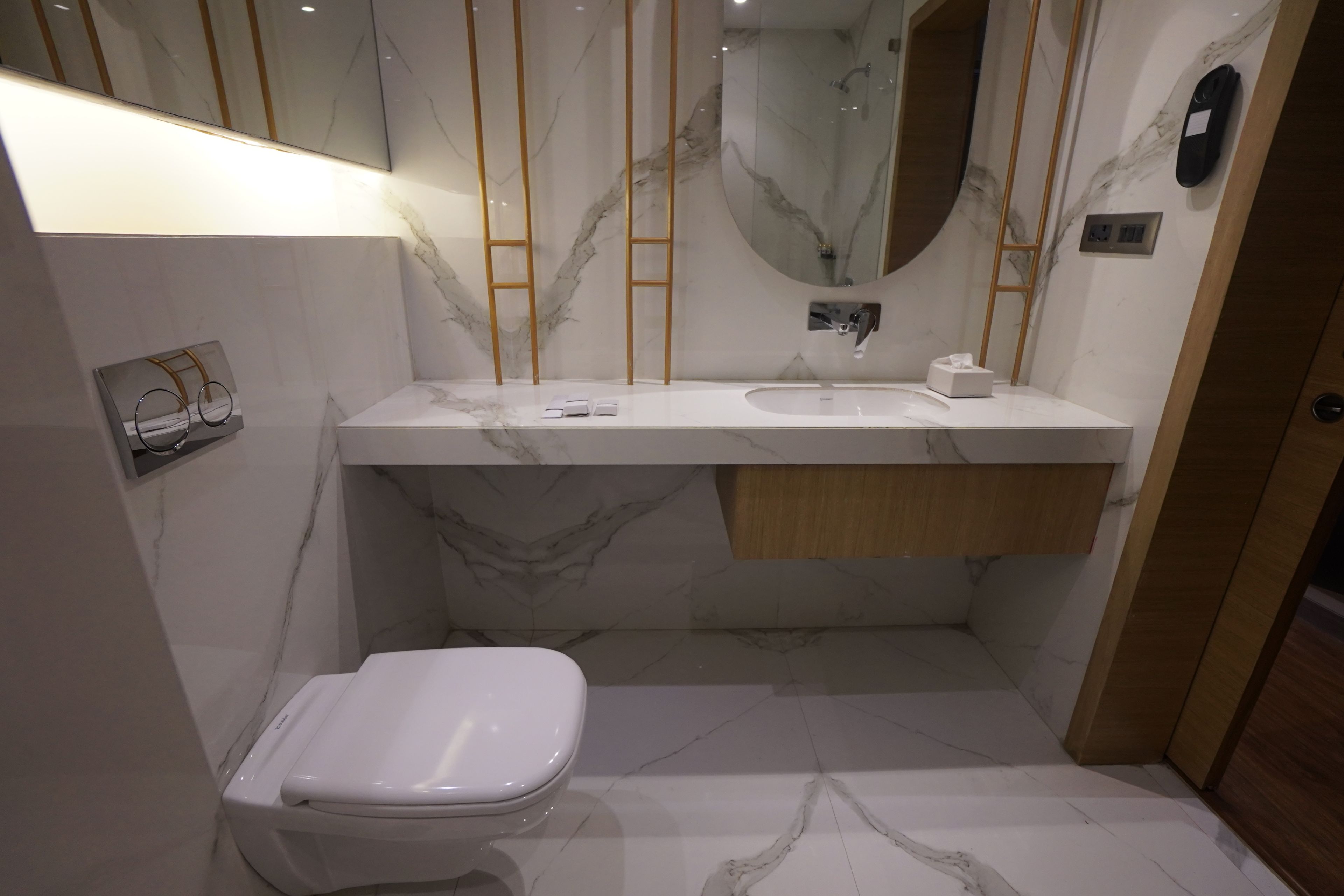 A modern bathroom with a white toilet, a marble sink, and a mirror.