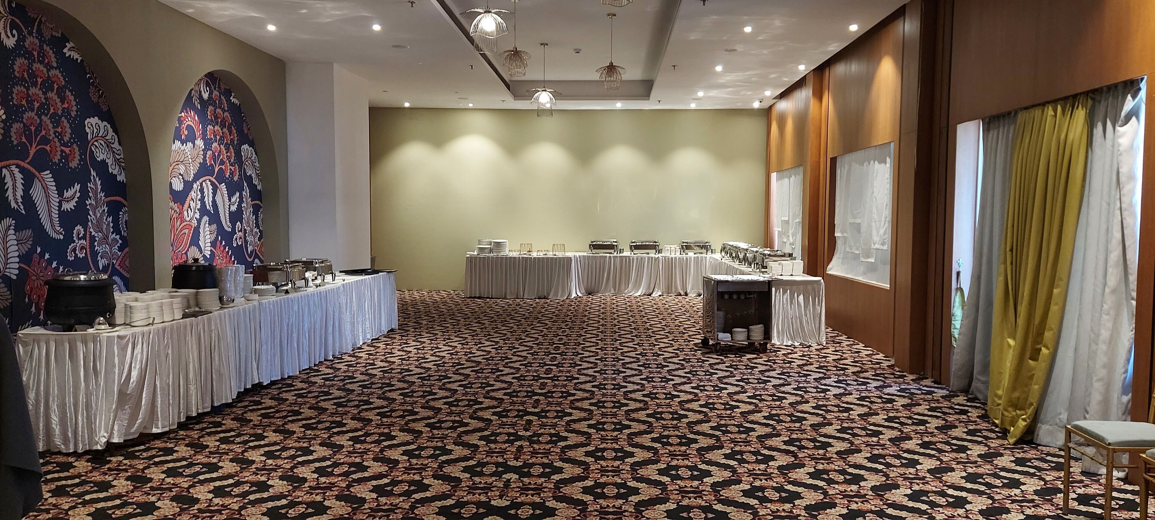 Una sala conferenze con una tappezzeria a motivi, tavoli apparecchiati per una riunione e un grande murale floreale sulla parete.