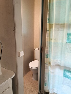 Een badkamer met een toilet, douchegordijn en handdoekhouder.