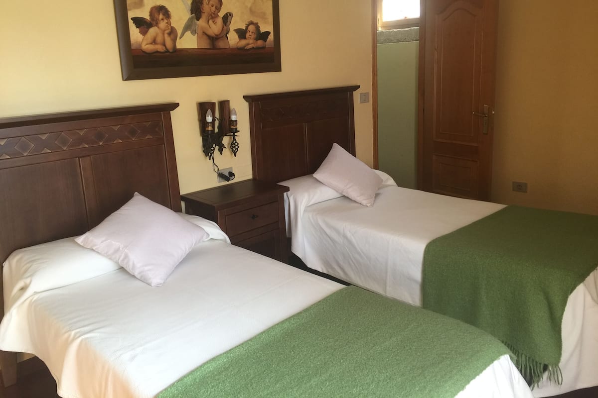 Habitación de hotel con dos camas, una mesita de noche, un cuadro y un espejo.