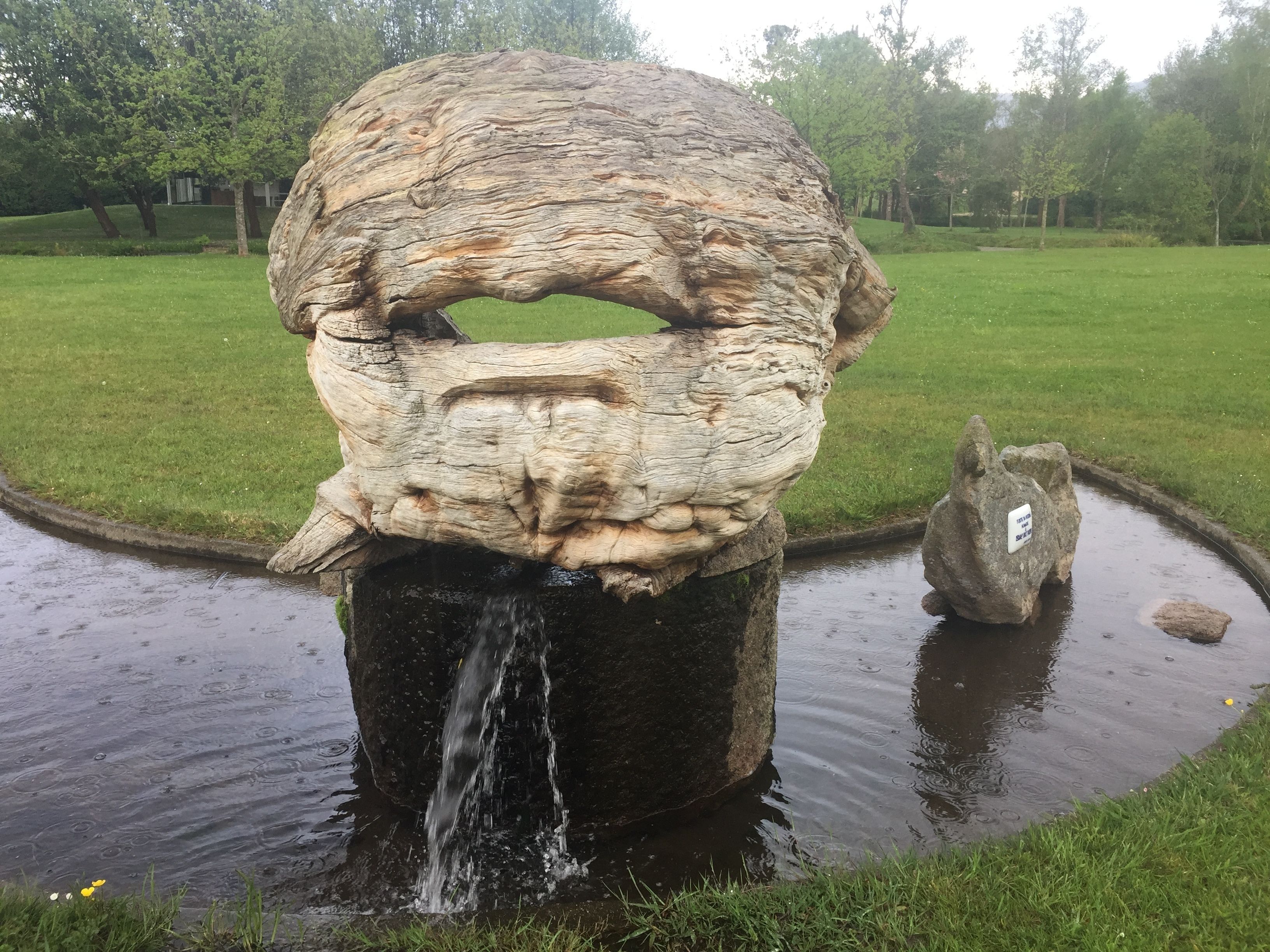 Een groot rotsbeeld met een waterval in een park.