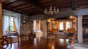 Un comedor rústico con mesa y sillas de madera, paredes de piedra y una araña.