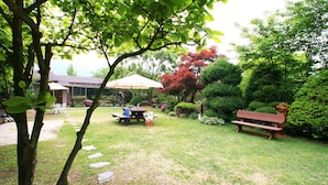 Ein Garten mit Picknicktisch, Bank und Sonnenschirm.