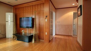 Ein Hotelzimmer mit Holzvertäfelung, einem Flachbildfernseher, einem schwarzen Konsolentisch und einem goldenen Zierbaum.