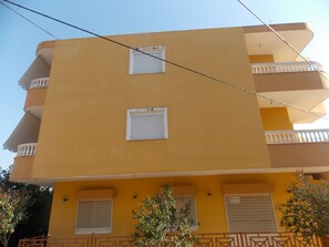 A yellow multi-story building with balconies and windows. - Yellow City Apartments (Sarandë)