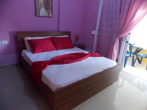 A bedroom with a wooden bed, white bedding, and a red throw blanket. - Yellow City Apartments (Sarandë)