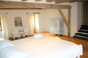 Cozy retreat with a large bed, vanity, and dresser, set against a wooden ceiling.