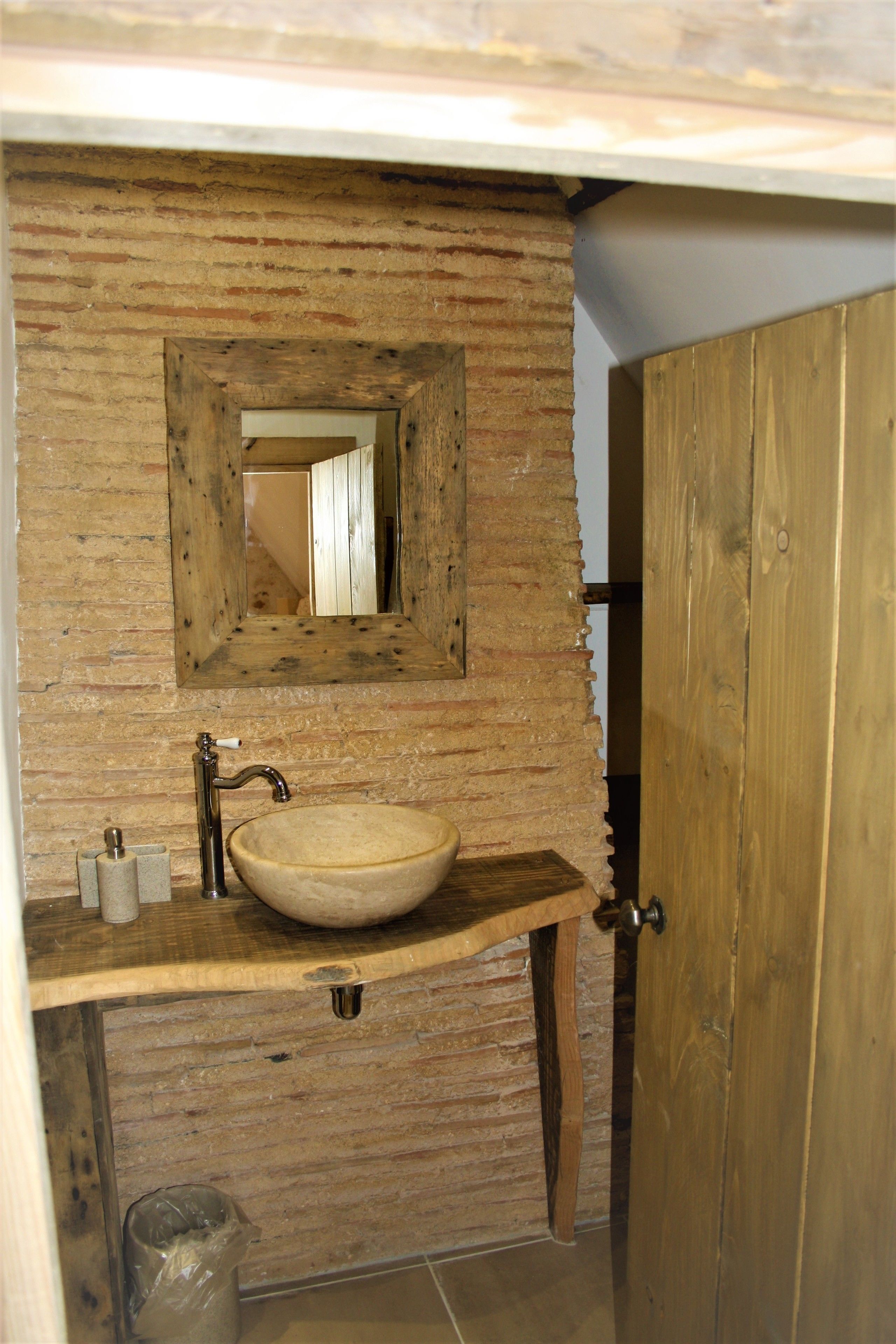 A rustic bathroom with a wooden vanity, a large mirror, and a single sink.