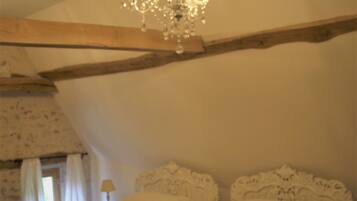 A bedroom with two beds, a chandelier, and a nightstand with a lamp.