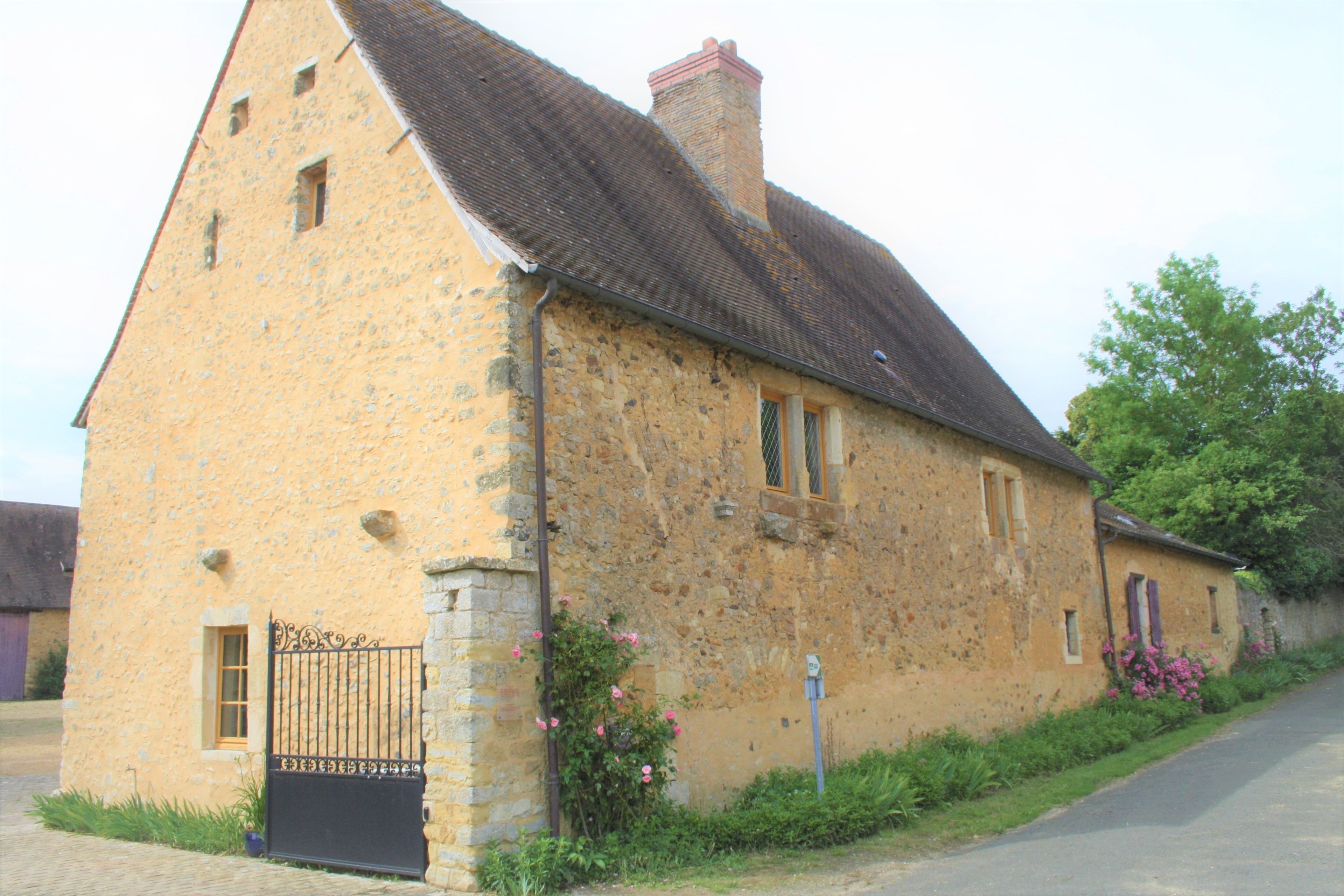 A stone building with a sloped roof, a gated entrance, and a small window.