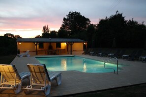 Relax by the pool surrounded by lounge chairs and a covered seating area.