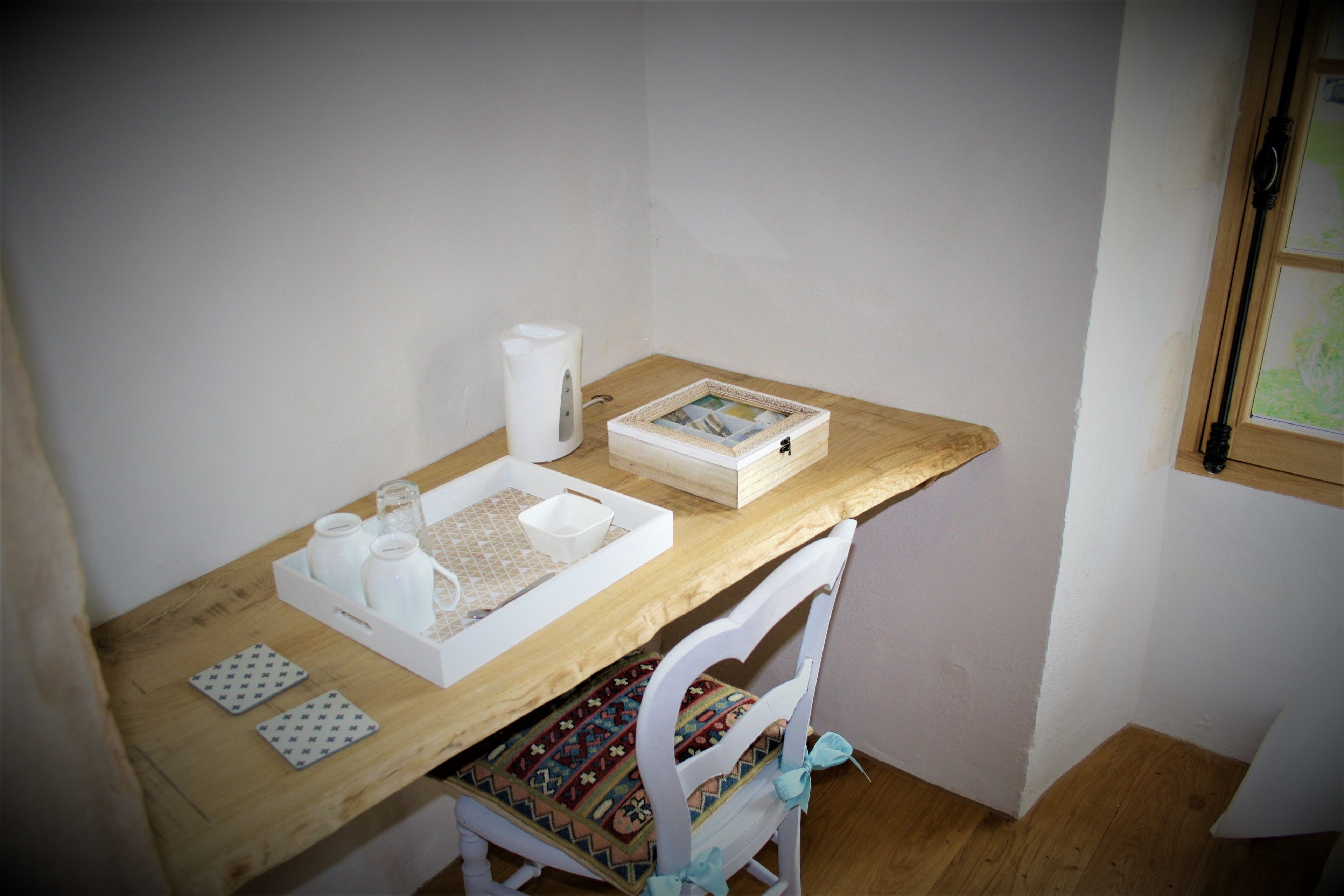 Un petit espace de travail bien rangé, avec un bureau en bois, une chaise blanche et un tableau encadré.