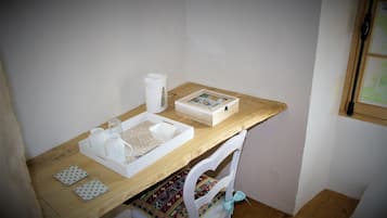 Un petit espace de travail bien rangé, avec un bureau en bois, une chaise blanche et un tableau encadré.