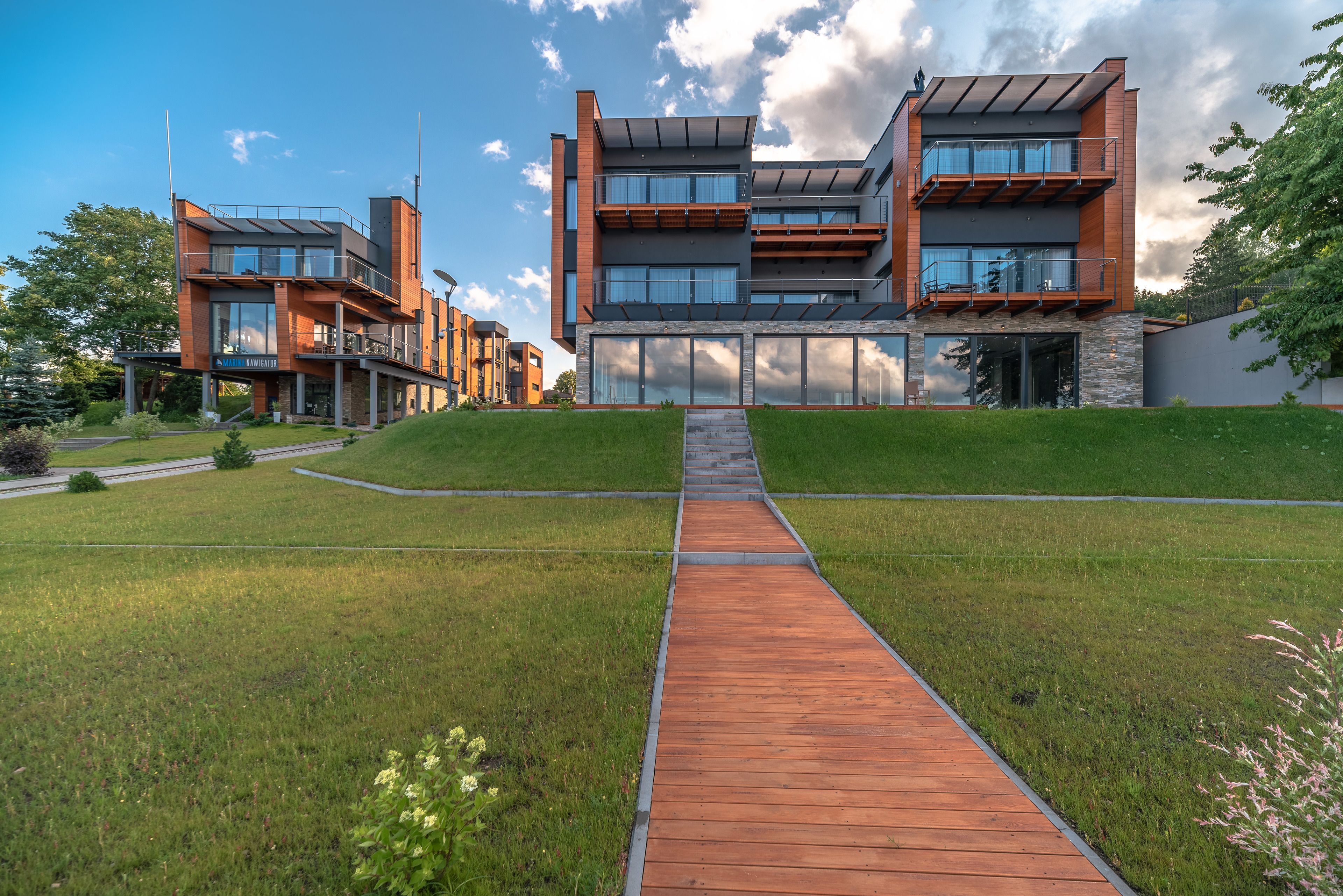 A modern multi-story building with a wooden pathway leading to the entrance.
