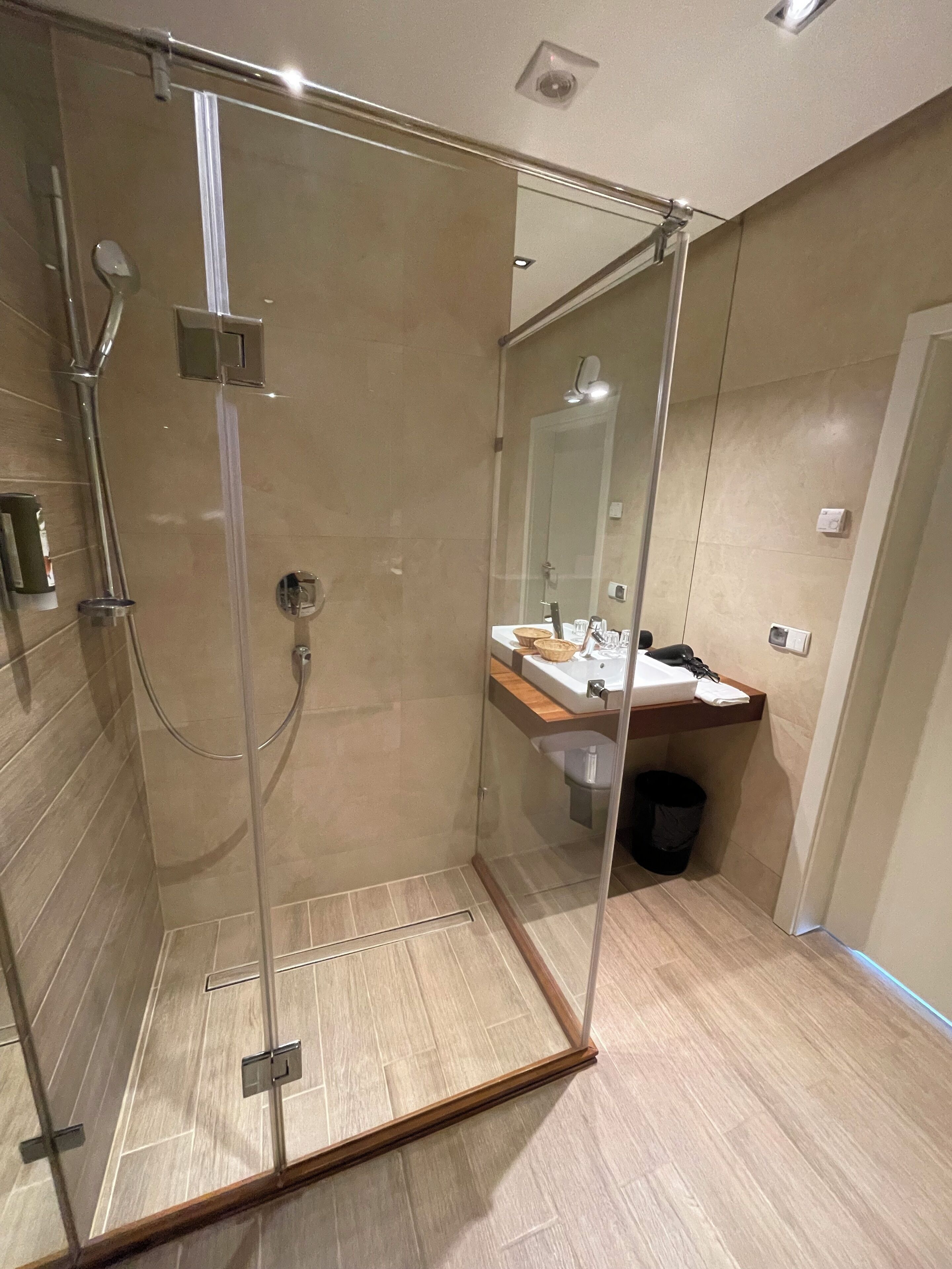 A modern bathroom with a glass-enclosed shower, a wooden vanity, and a mirror above the sink.