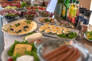 A buffet table with various food items including cheese, eggs, olives, and meats.