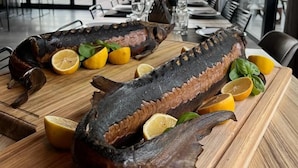 Un plato de mariscos con rodajas de limón sobre una mesa de madera en un restaurante con vista al mar.