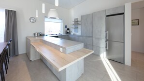 A modern kitchen with a central island, stainless steel appliances, and a large window. - Húsafell Holiday Homes (Borgarbyggd)