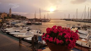 A marina with boats docked, a bell tower, and a sunset in the background. - B&B Kalimaka (San Giovanni a Piro)
