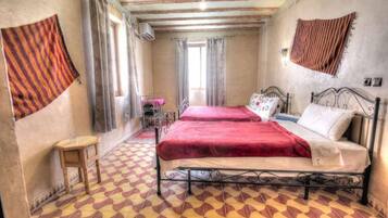 Une chambre avec deux lits, une petite table et un sol à motifs.