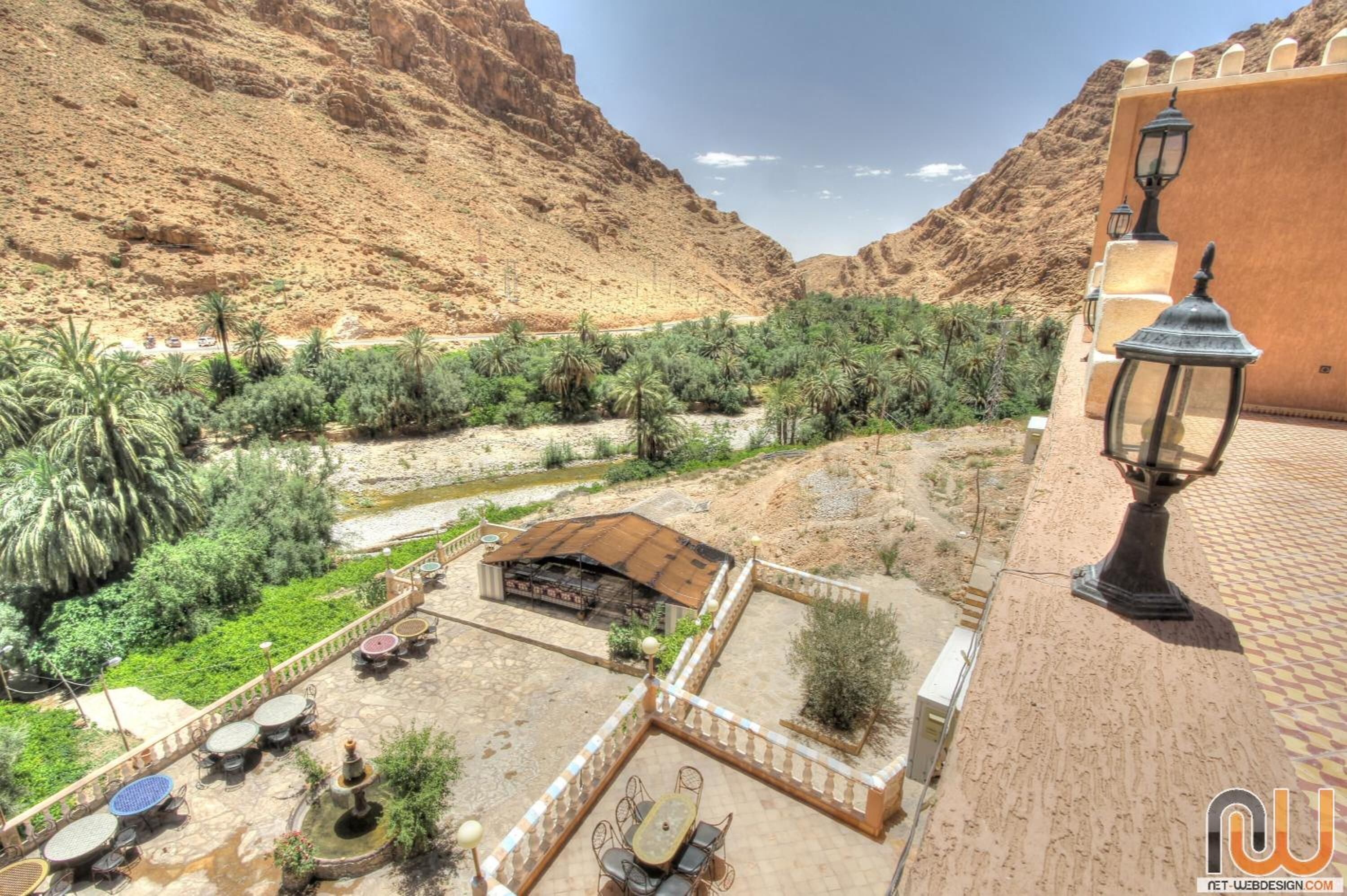 A courtyard with outdoor seating, a water feature, and a view of a mountainous landscape.