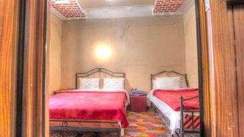 A room with two beds, a small table, and a patterned floor.