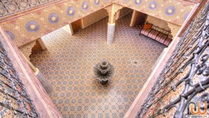 Un interior ornamentado con intrincados diseños de azulejos, una columna decorativa central y una zona de estar.