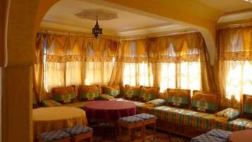 A room with a round table, a sofa set, and a patterned carpet.