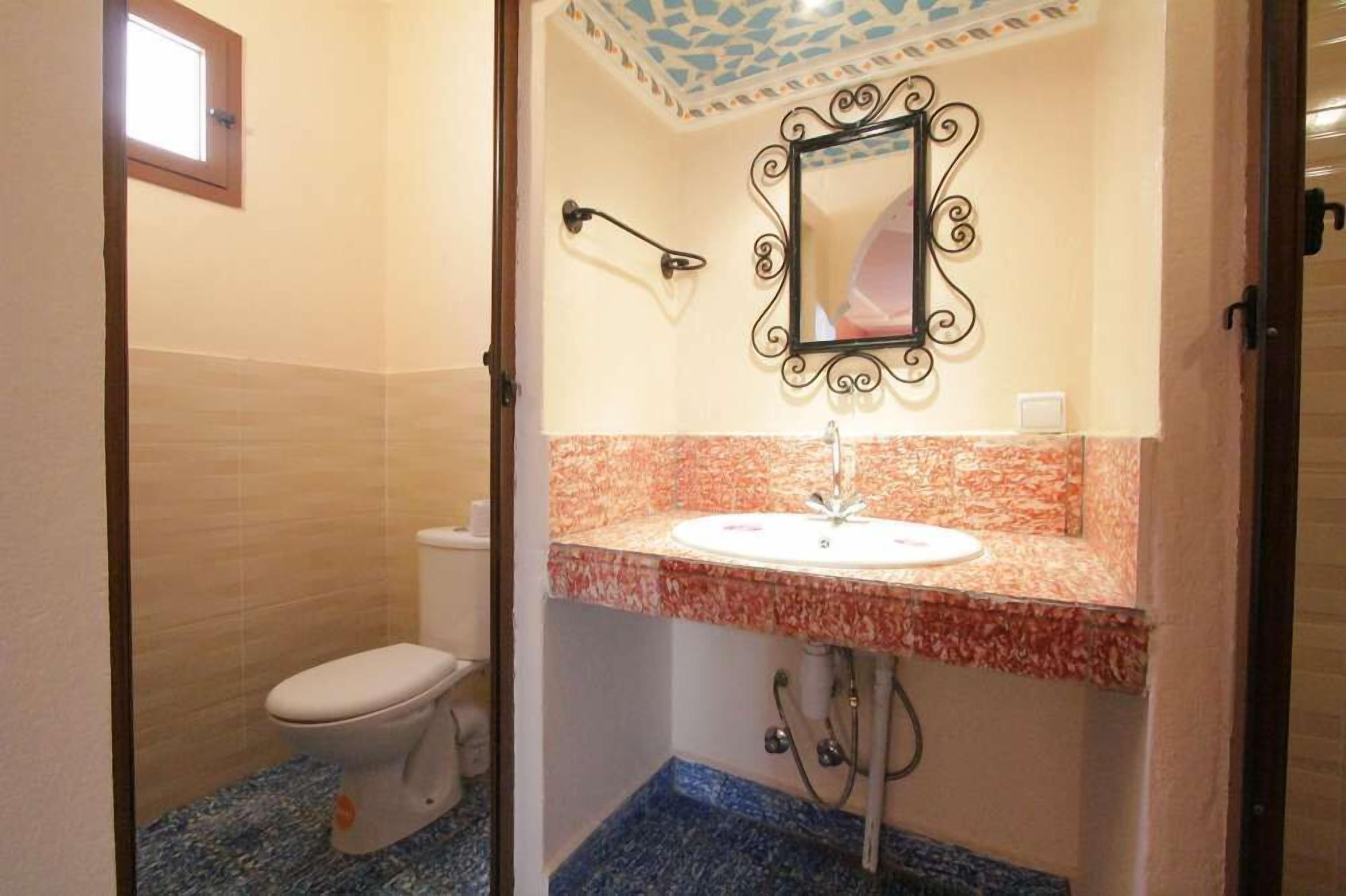 Un baño con inodoro, lavamanos y espejo.