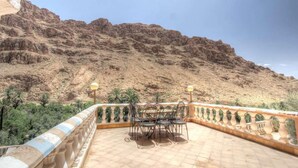 Una terraza con mesa y sillas, con vistas a una ladera rocosa.