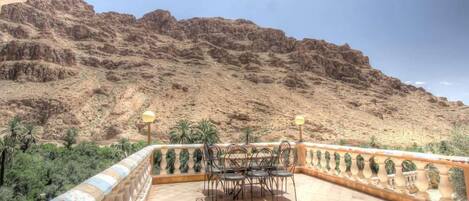 Una terraza con mesa y sillas, con vistas a una ladera rocosa.