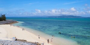 A beach with clear turquoise water, a sandy shore, and a few people enjoying the water. - Shiawaseninaru Kourijima no Yado (Nakijin)