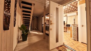 A wooden hallway with a staircase, a potted plant, and a door leading to another room.