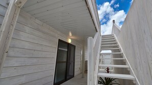 A wooden exterior with a glass door and a white staircase leading to a higher level.