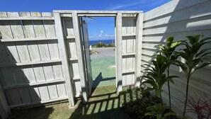 A wooden gate leading to a yard with a view of the ocean.
