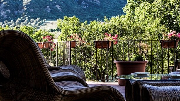 A terrace with wicker furniture, a glass table, and potted plants. - Agriturismo Aurea (Crucoli)