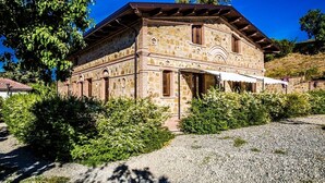 A stone building with a sloped roof, arched windows, and a gravel driveway. - Agriturismo Aurea (Crucoli)