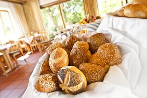 A variety of breads in a basket, with a dining area in the background.