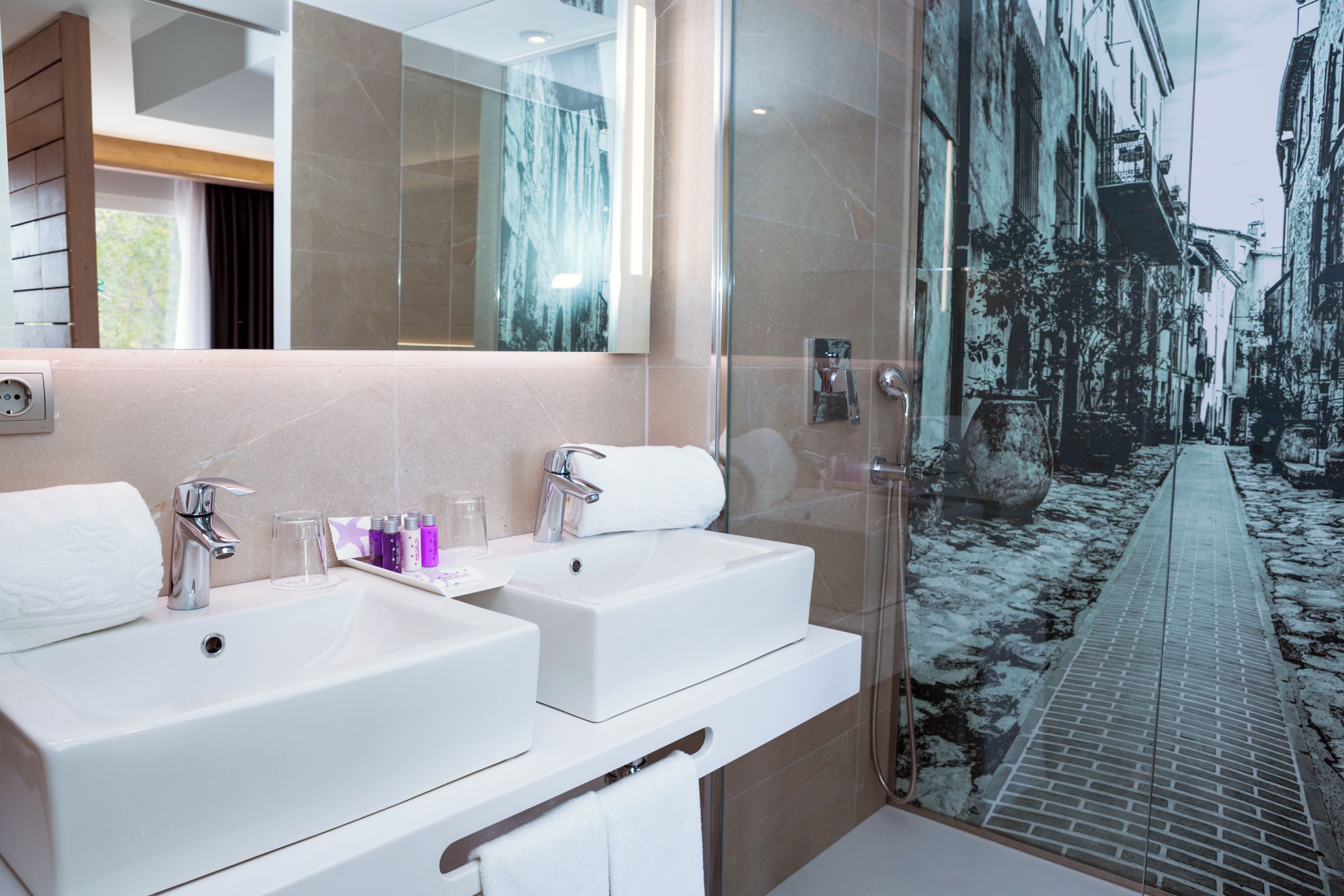A modern bathroom with two sinks, a large mirror, and a shower.