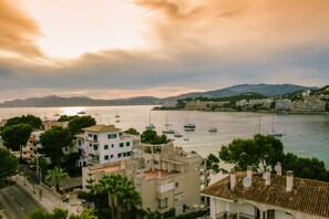 A coastal town with buildings along the waterfront, boats in the water, and mountains in the background. - Bahia del Sol (Calvia)