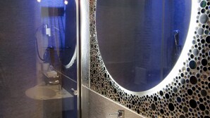 A modern bathroom with a large mirror, a white sink, and a glass-enclosed shower. - Affittacamere Opera House (Rome)