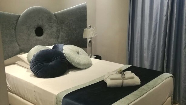 A neatly made bed with a headboard, pillows, and a blanket. - Affittacamere Opera House (Rome)