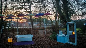 An outdoor setting with a white sofa, a mirror, and colorful umbrellas.