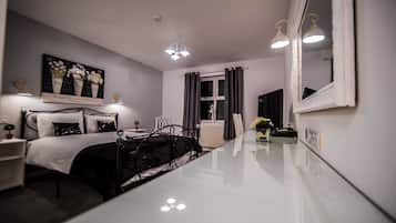 Habitación de hotel con cama, mesita de noche, lámpara y un espejo grande.