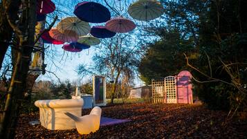 Ein Garten mit verschiedenen Sonnenschirmen, einer weißen Skulptur und einem Metalltor.