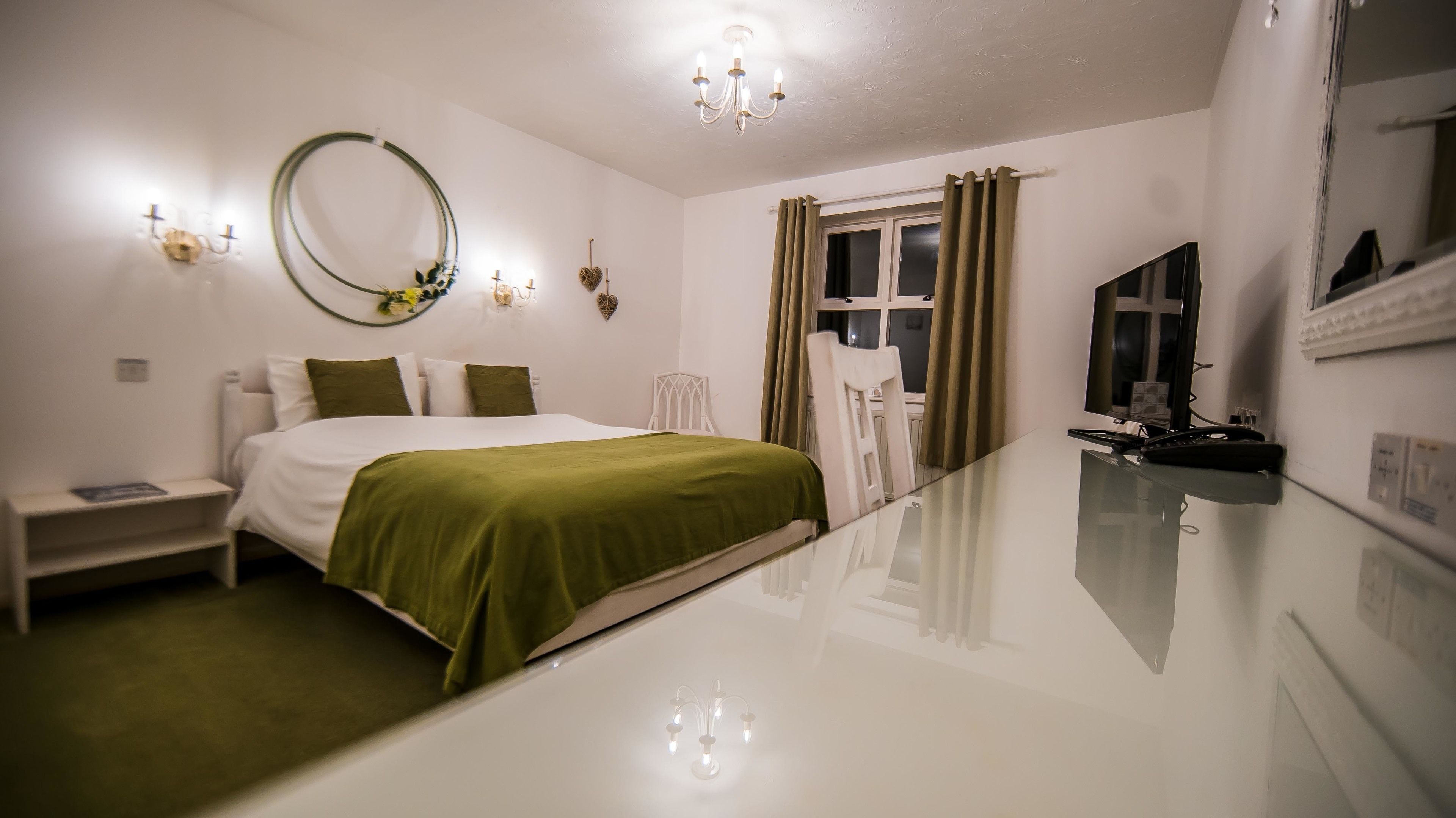 A hotel room with a bed, bedside table, and a TV.