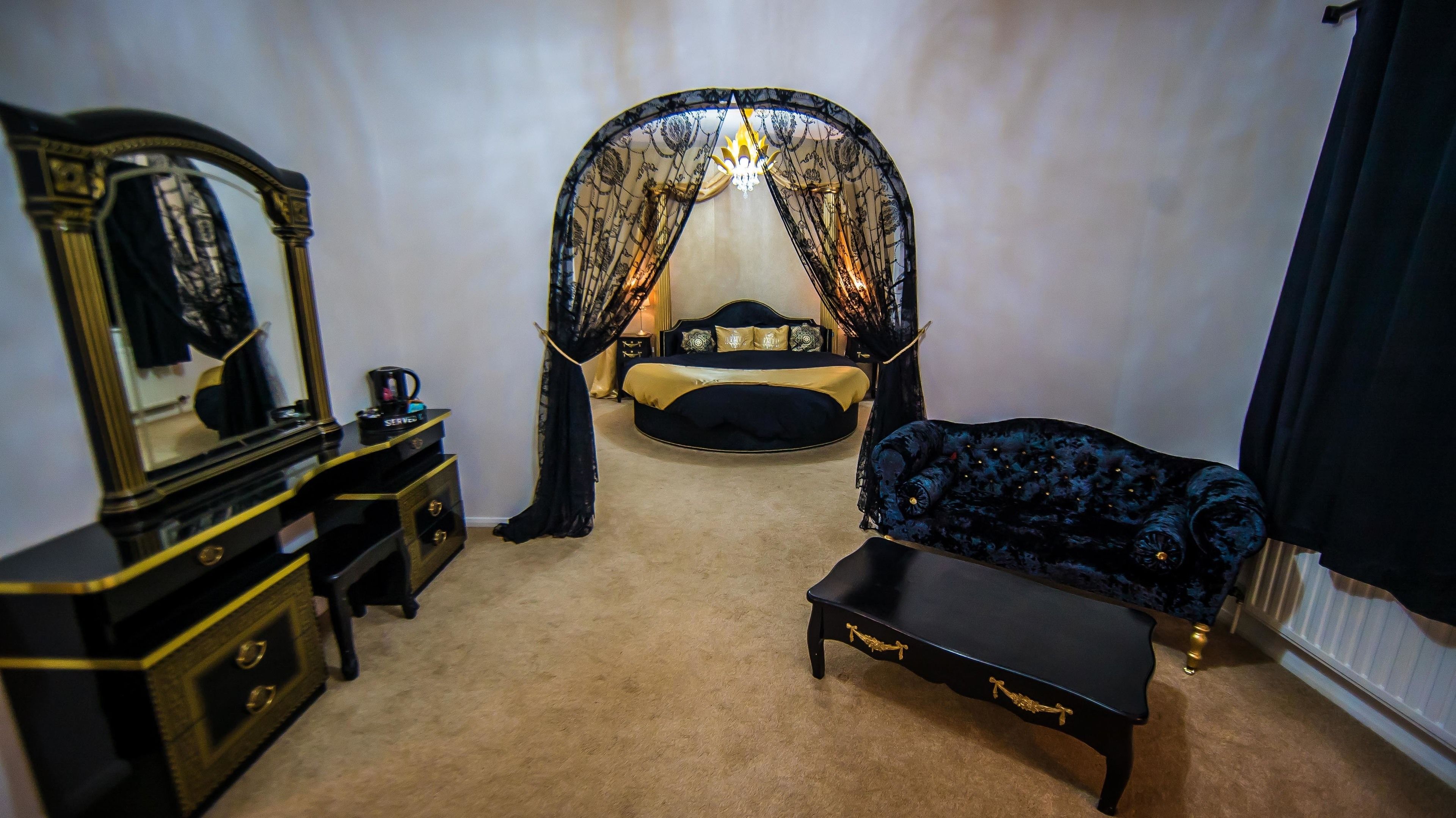 A bedroom with a bed, a vanity with a mirror, a bench, and a canopy.